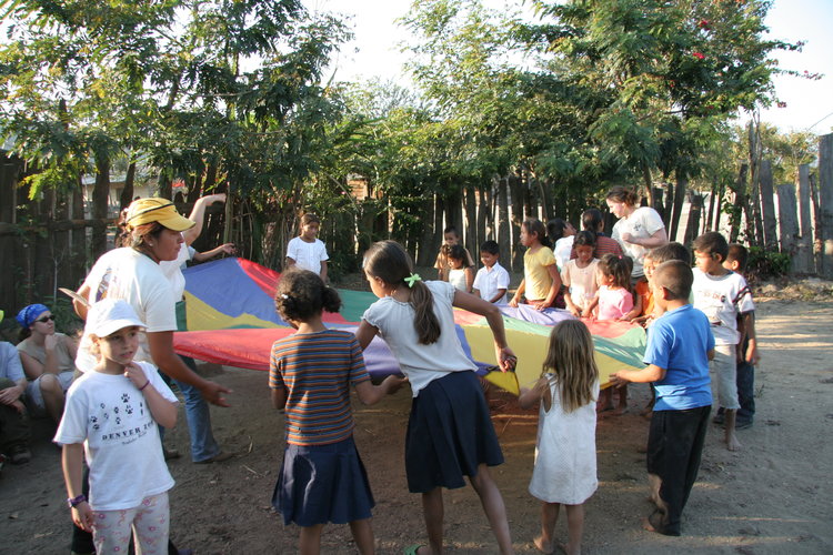 Photo of children playing outside with a parachute.