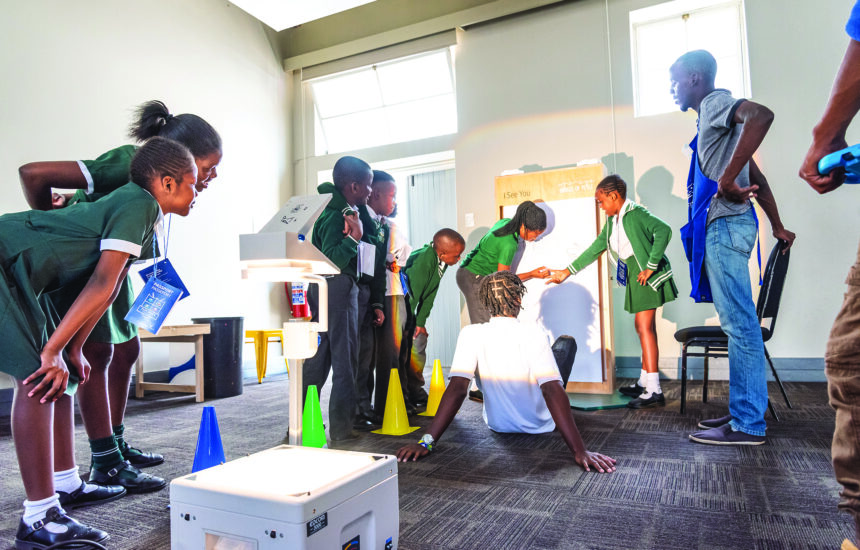 A group of students in a classroom with a teacher, working on a project