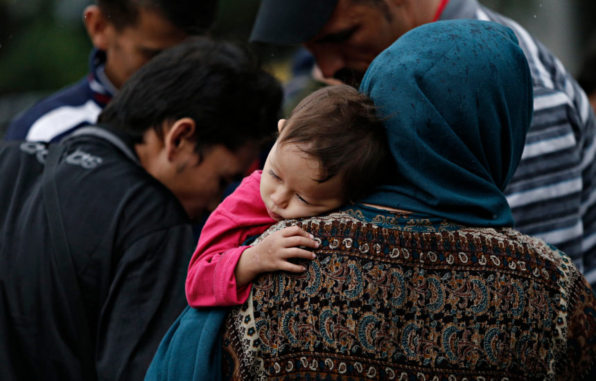 A woman carries a tired child