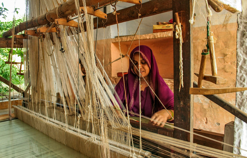 A woman works with a weaving machine