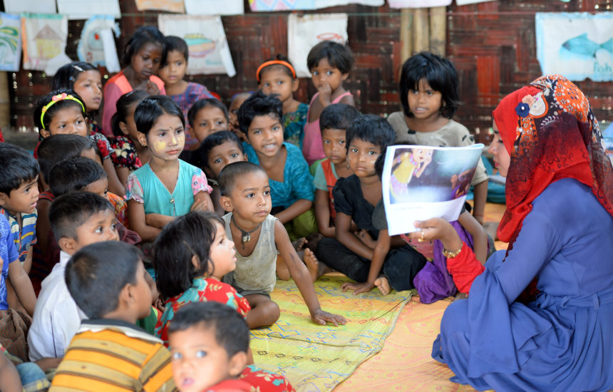 A woman reads a book to a group of children