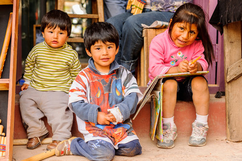 A group of children sitting outside, smiling.