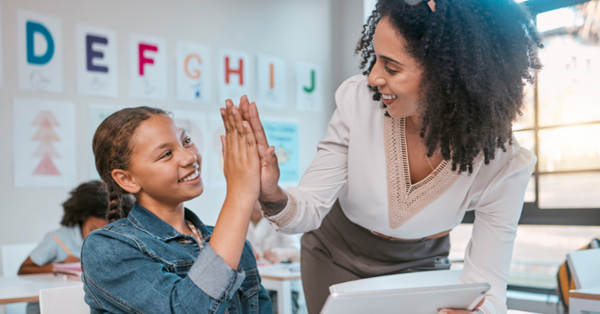 A teacher and a student, smiling and giving each other a high five