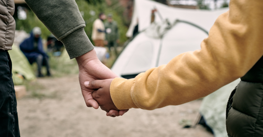 Adult and child holding hands in a refugee camp