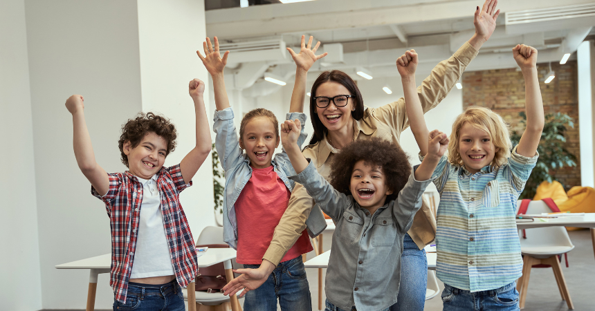 Happy teacher with children, raising hands in the air